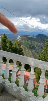 Distant city and mountains viewed from a scenic balcony with lush greenery.