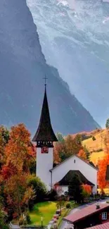 Scenic autumn village with church under a foggy mountain backdrop.