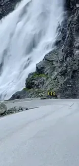 Mountain road with stunning waterfall backdrop.