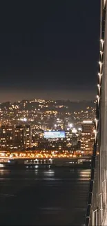 Nighttime cityscape with illuminated bridge and skyline view.