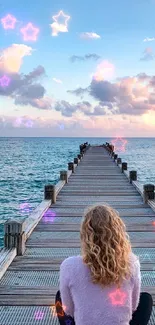 Woman sitting on pier with ocean, clouds, and stars.