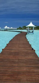 A tranquil ocean pier extending over turquoise waters with a clear blue sky background.