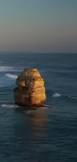 Serene ocean scene with a lone rock formation at sunset.