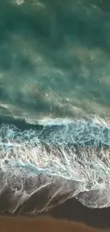 Aerial view of teal ocean waves crashing on a sandy beach.