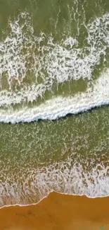 Aerial view of ocean waves crashing onto a sandy beach, perfect for mobile wallpaper.