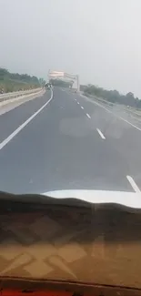 Open highway under a gray sky with surrounding green forests.