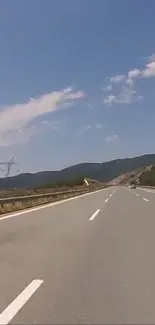 Scenic open road under a blue sky leading towards mountains.