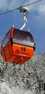 Orange cable car in snow-covered landscape with blue sky.