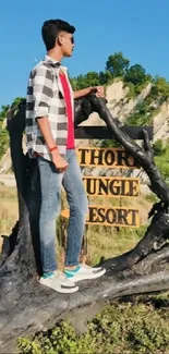 Man standing on a tree with scenic mountain view.