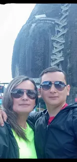 Couple exploring a scenic mountain backdrop with sunglasses on a bright day.