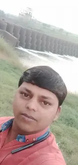 Person near scenic dam amidst lush greenery.