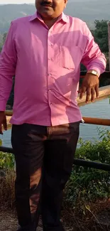 Person in pink shirt with scenic outdoor backdrop.