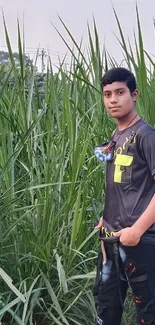 Young man standing in lush green field under a calm sky.