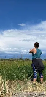 Person enjoying nature with scenic sky and field landscape.