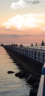 Pier leading into sunset with pastel sky over calm water.