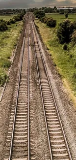 Scenic railway tracks with green fields and cloudy sky