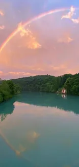 A vibrant rainbow arches over a serene river landscape with lush green forests.