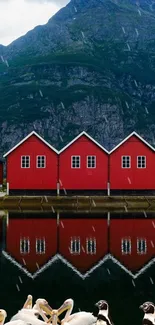 Red houses with mountain backdrop reflecting in water.