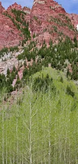 Red mountain with green trees under a blue sky.