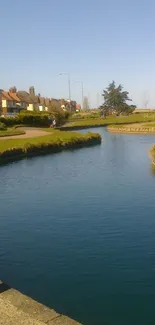 Serene river with lush greenery and village houses under a clear sky.