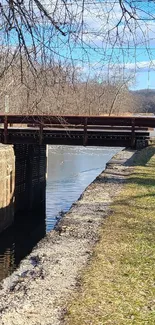 Rustic bridge over a tranquil river on a sunny day.