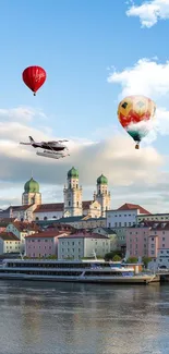 Hot air balloons over a scenic river cityscape with historic architecture.