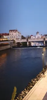 A serene evening city view over a river with a bridge and glowing lights.