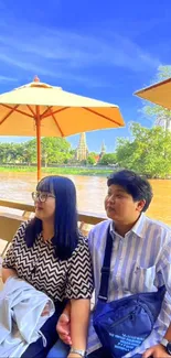 Serene view of couple by riverside under umbrellas.