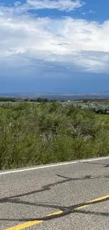 Scenic road under a blue sky with lush green landscape.