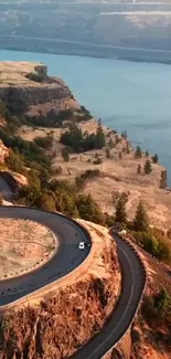 Scenic view of winding road by the cliffside along a serene body of water.