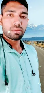 Man with headphones on a scenic road with mountains.