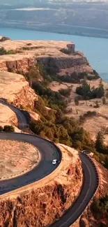 Aerial view of a winding road on a cliff with river in background.