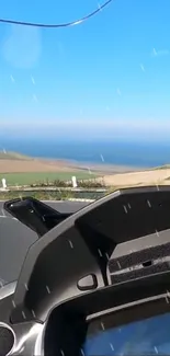 A scenic road trip view with ocean and blue sky, ideal for mobile wallpaper.