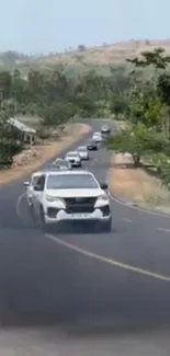 Cars on a scenic winding road surrounded by lush greenery.