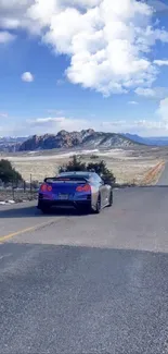 Blue sports car on a scenic desert road under a clear sky.