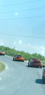 Scenic road with sports cars under a blue sky.