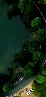 Aerial view of a winding road by a blue lake and green forest.