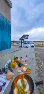 Outdoor cooking scene with van and scenic sky.