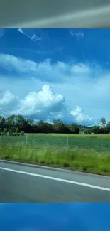 Vibrant countryside under a blue sky with clouds, viewed from the roadside.