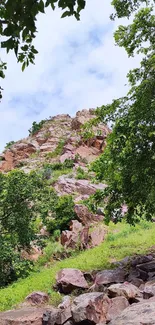 Rocky hill with greenery and a blue sky.