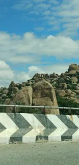 Scenic view of rocky hillside under a vivid blue sky with fluffy clouds.