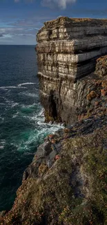 Dramatic rocky ocean cliffs under blue skies.