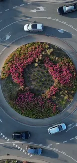 Aerial view of a roundabout with cars and lush flowers.