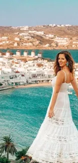 Woman in white dress overlooking a scenic seaside with turquoise waters.