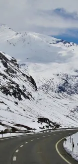 Winding road through snowy mountains under a clear sky.