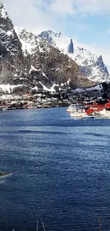 Scenic fjord with snowy mountains and red cabins.