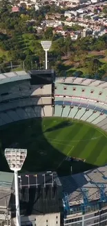 Aerial view of a large stadium with green surroundings and clear sky.