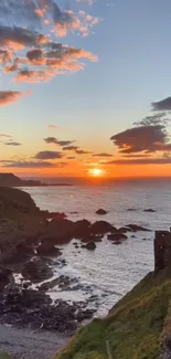 A breathtaking sunset over a rocky coastline with vibrant orange hues.