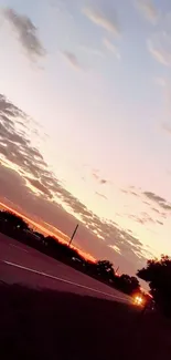 A tranquil sunset view over a countryside road with vibrant sky colors.