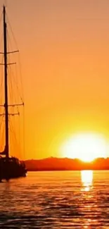 Sailboat on a tranquil orange sunset backdrop with serene water.